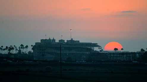 The sun is a blazing ball of orange as it sets behind Del Mar Racetrack.